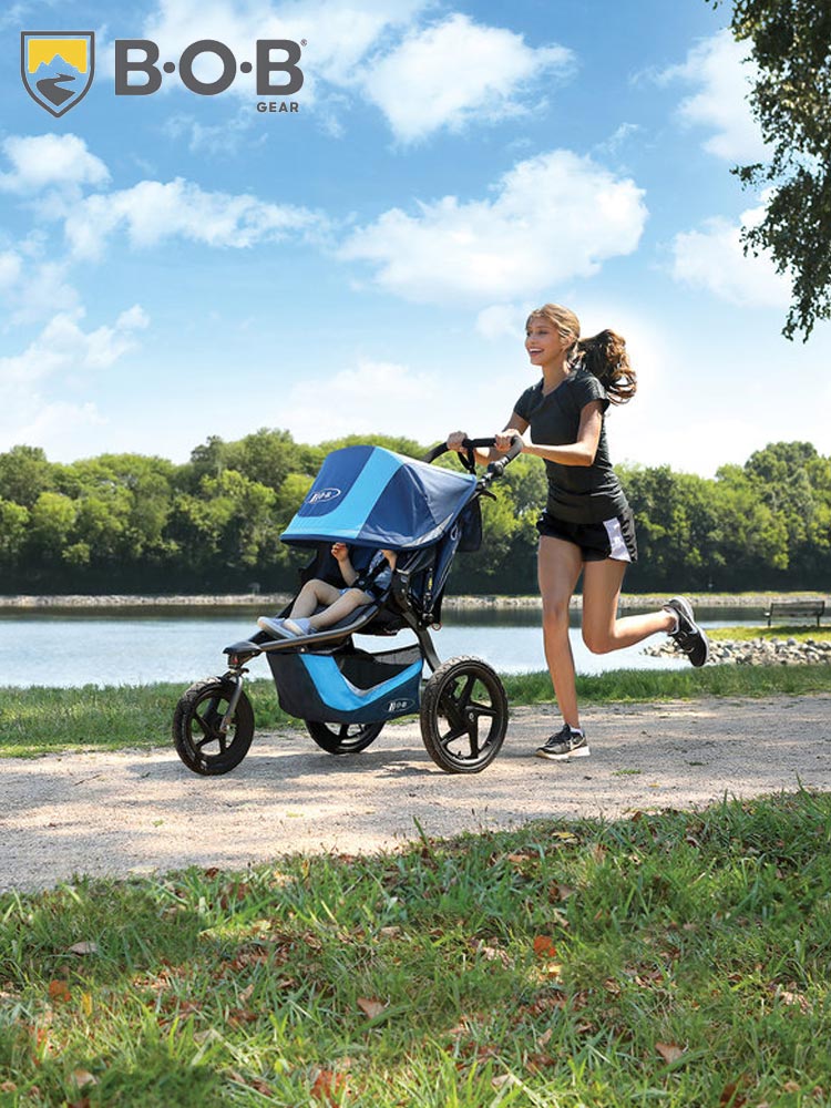 mom jogging in a park with a toddler sitting in the bob revolution flex 3.0 stroller