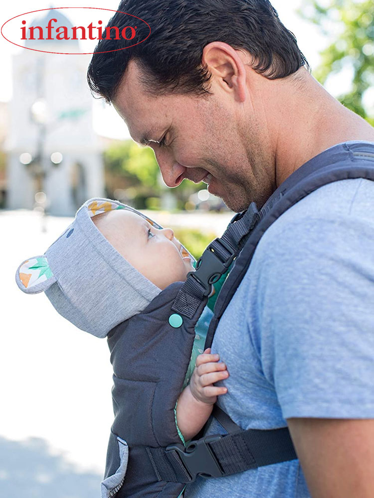 a father looking down at a baby in an infantino cuddle up baby carrier