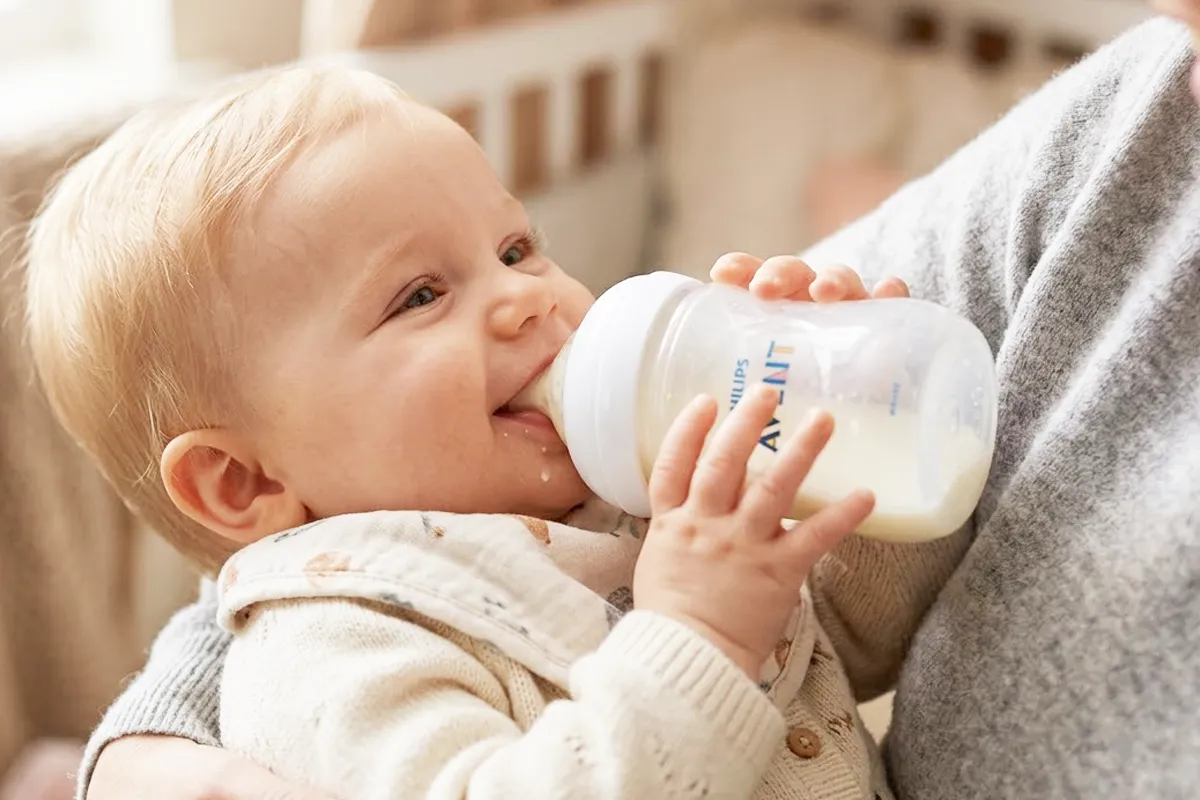 mom bottle feeding her baby in a nursery with the best organic baby formula