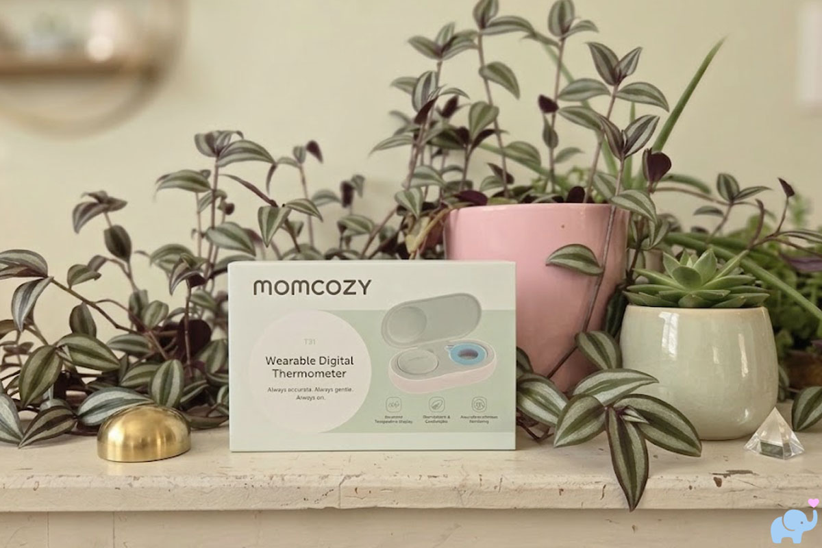 momcozy smart baby thermometer box on a table with plants behind it